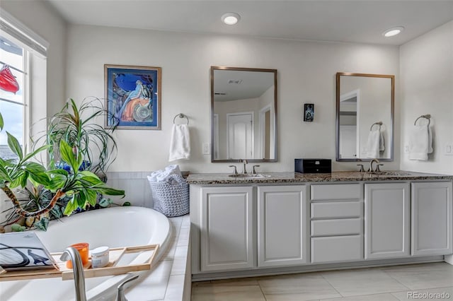 full bathroom with a tub, double vanity, and recessed lighting