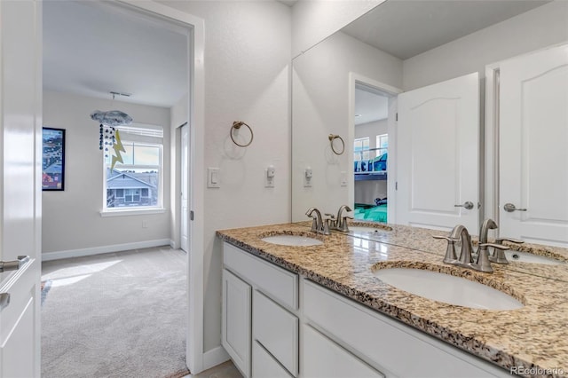 full bath featuring double vanity, plenty of natural light, and baseboards