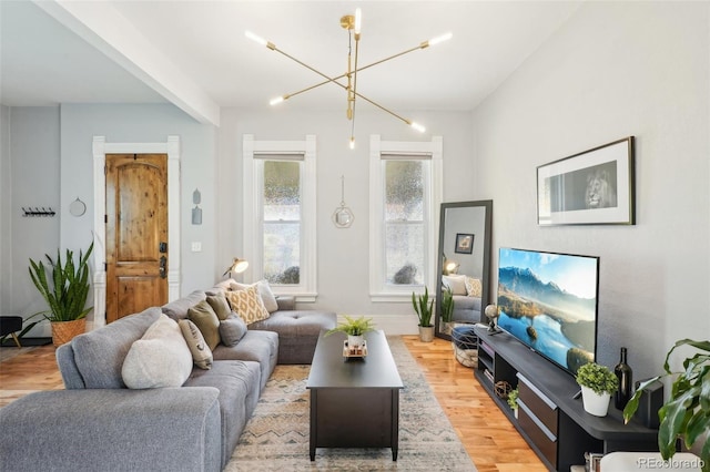 living area featuring light wood-type flooring, a chandelier, and baseboards