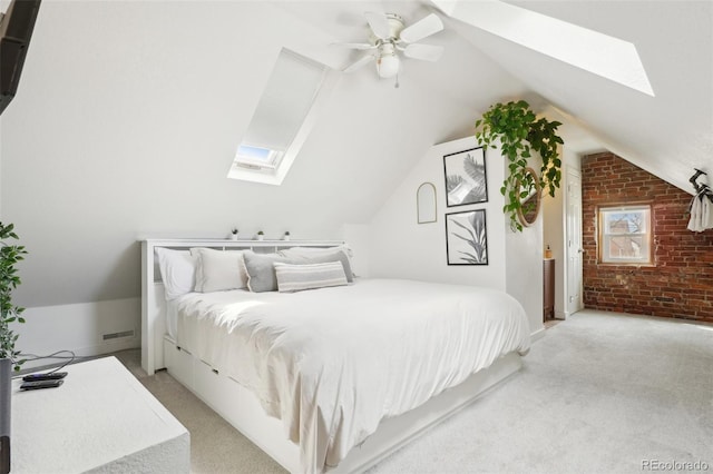 bedroom featuring a skylight, brick wall, light colored carpet, lofted ceiling, and a ceiling fan