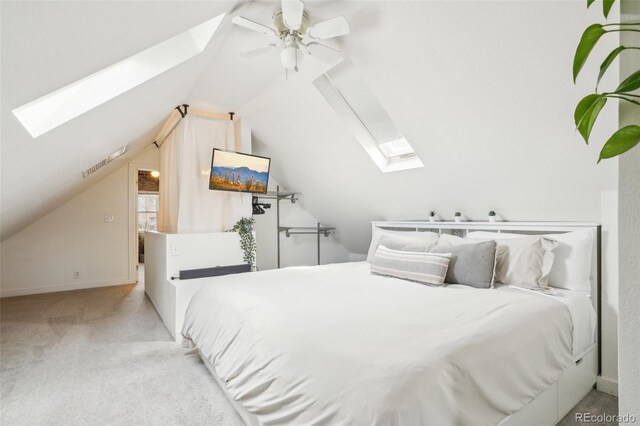 bedroom with a skylight, vaulted ceiling, carpet floors, a ceiling fan, and baseboards