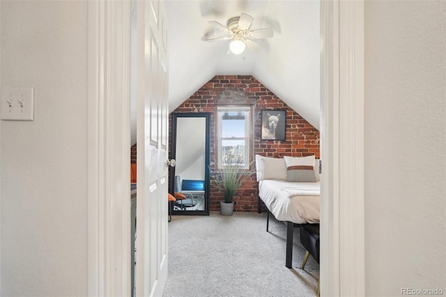 carpeted bedroom with lofted ceiling, a ceiling fan, and brick wall