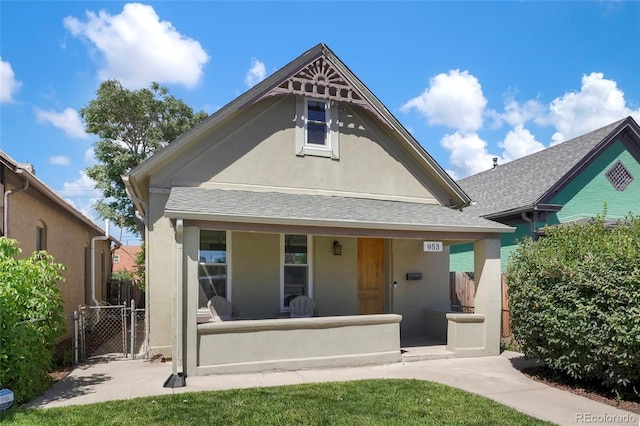 view of front of home with a porch, stucco siding, a gate, fence, and roof with shingles