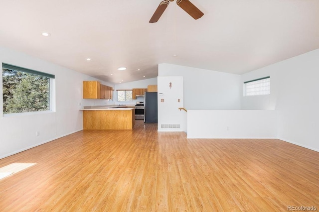 unfurnished living room featuring lofted ceiling, light wood-type flooring, and ceiling fan