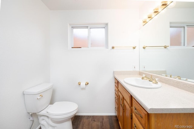 bathroom with toilet, vanity, and hardwood / wood-style floors