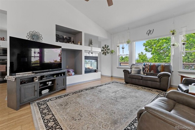 12277 W Chenango Dr, Morrison, CO 80465 - living area featuring light wood finished floors, ceiling fan, high vaulted ceiling, and built in shelves