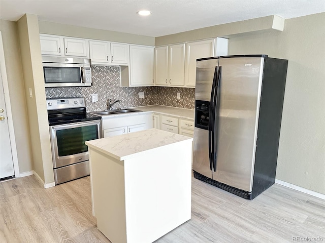 kitchen with backsplash, light wood finished floors, appliances with stainless steel finishes, and a sink