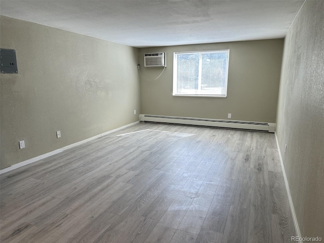 empty room featuring electric panel, wood finished floors, a wall mounted air conditioner, and a baseboard radiator