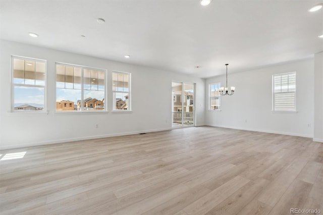 unfurnished dining area featuring light wood-style flooring, a wealth of natural light, and an inviting chandelier