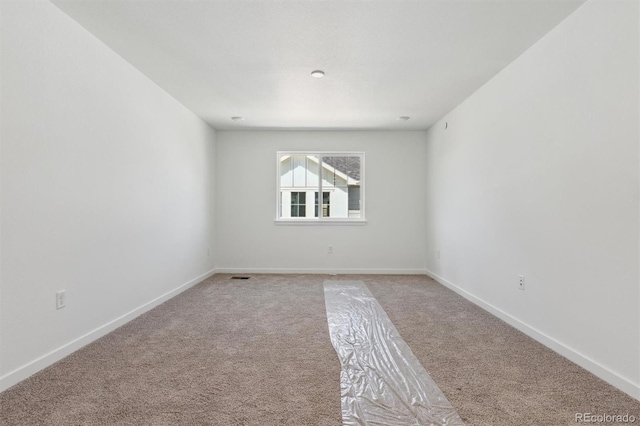 unfurnished room with light carpet, visible vents, and baseboards