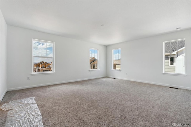 carpeted spare room with plenty of natural light, baseboards, and visible vents