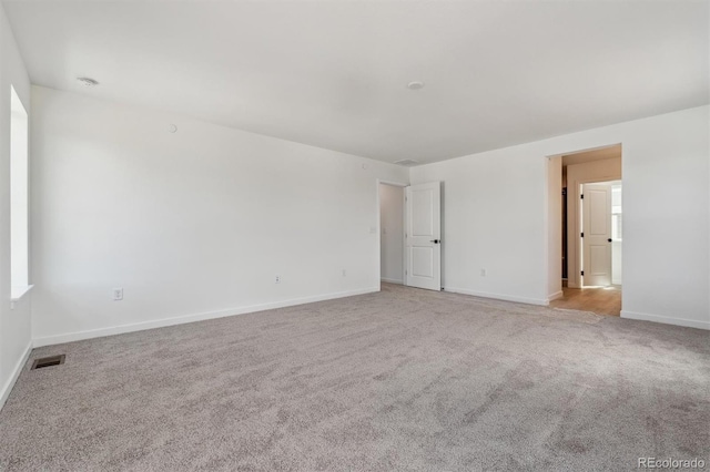 unfurnished room with light colored carpet, baseboards, and visible vents