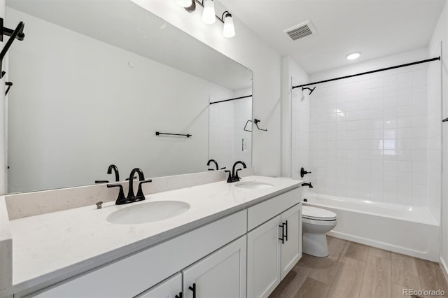 bathroom with wood finished floors, visible vents, a sink, and toilet