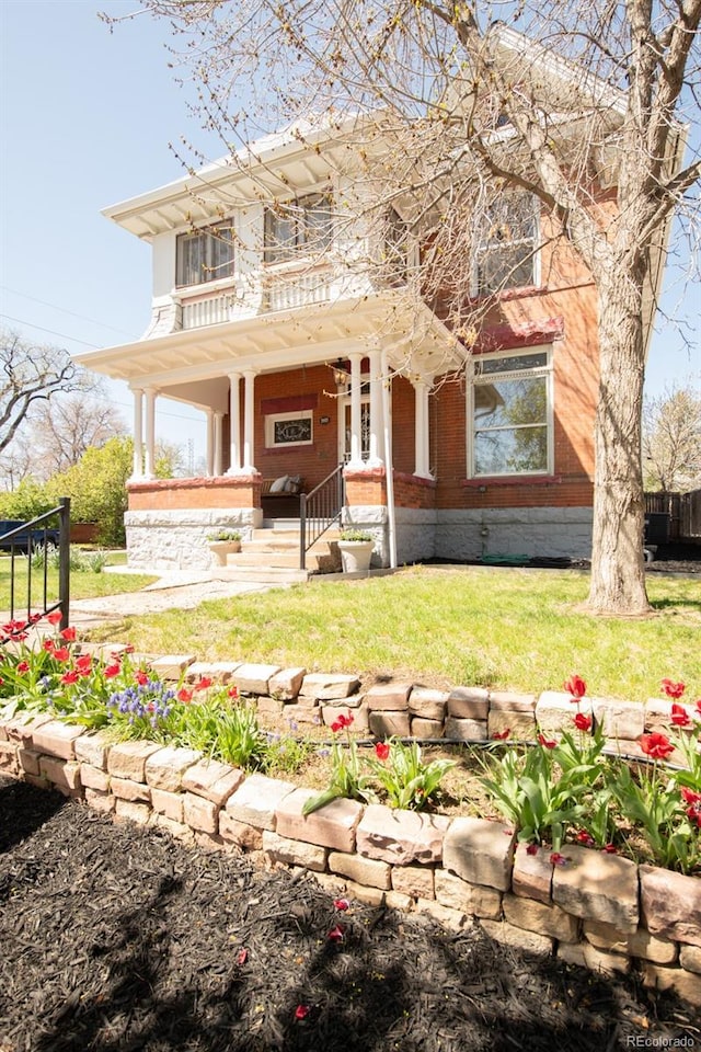 view of front of property featuring covered porch, brick siding, and a front lawn