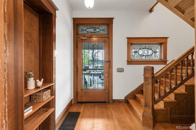 doorway with stairway, baseboards, wood finished floors, and visible vents