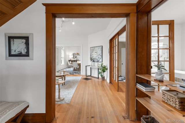 hallway with baseboards, french doors, and light wood-style flooring
