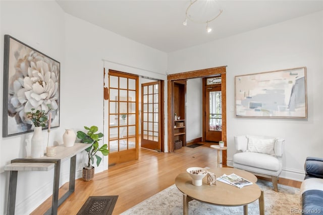 living area featuring baseboards, french doors, and wood finished floors