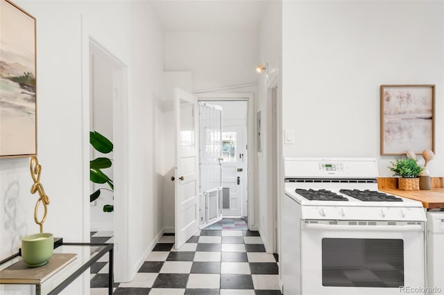 kitchen with white range with gas stovetop, white cabinets, and dark floors