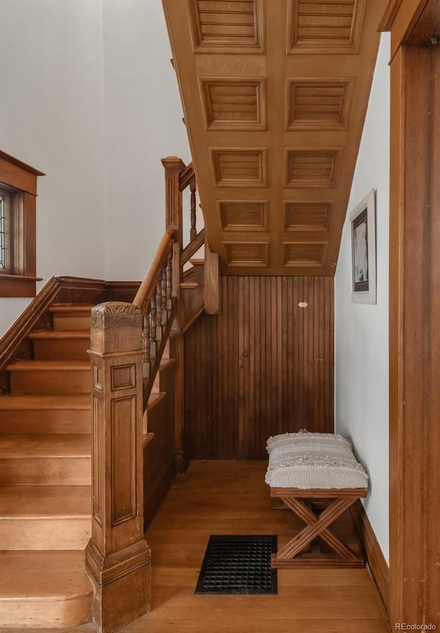 staircase featuring wood walls, wood finished floors, and visible vents