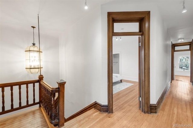 hall with baseboards, light wood finished floors, and an upstairs landing