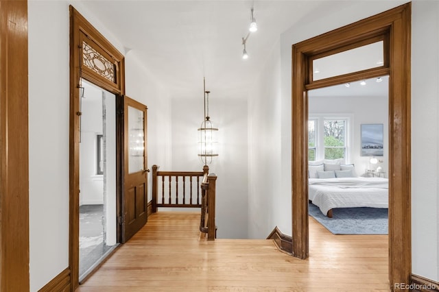 hall with an upstairs landing and light wood-type flooring