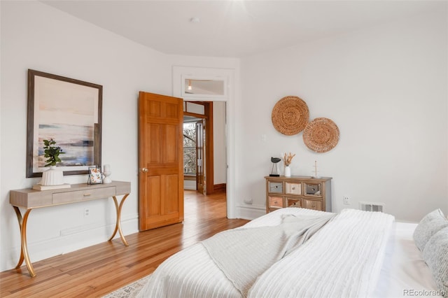 bedroom featuring baseboards, wood finished floors, and visible vents