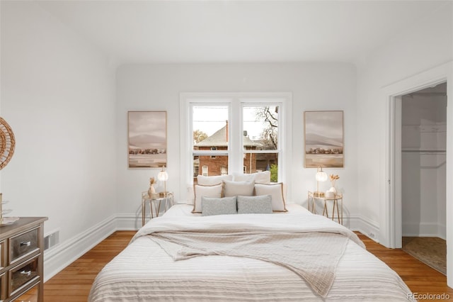 bedroom with visible vents, baseboards, wood finished floors, and a closet
