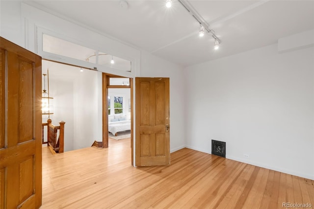 empty room featuring light wood-type flooring and rail lighting