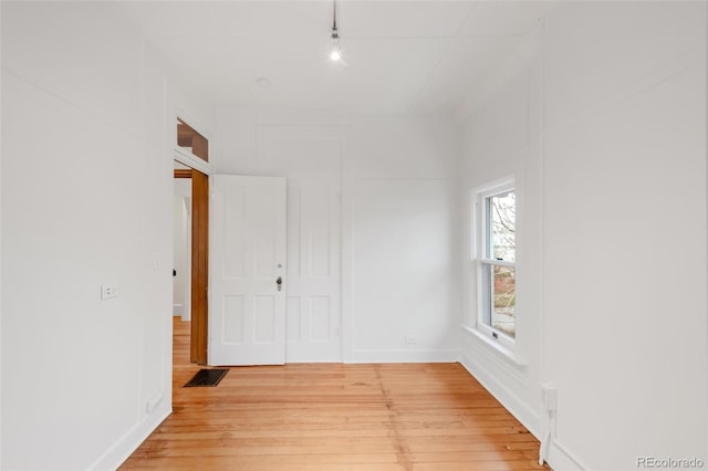 empty room featuring visible vents, rail lighting, light wood finished floors, and baseboards