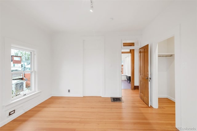 unfurnished bedroom featuring visible vents, baseboards, a closet, and light wood-type flooring