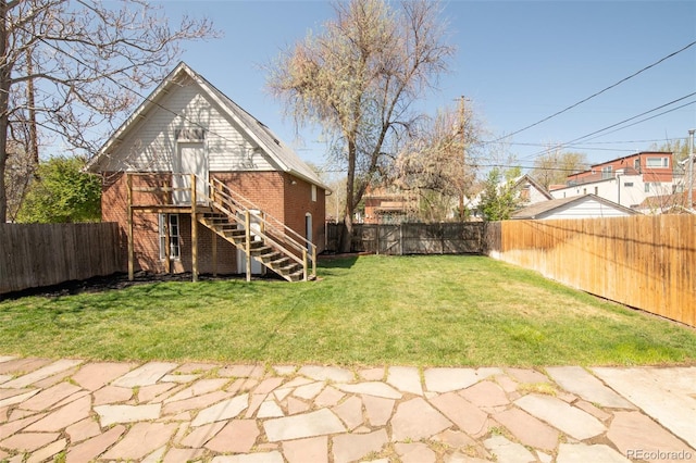 view of yard with a fenced backyard and stairway