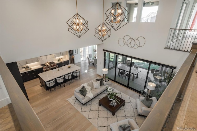 living area featuring a high ceiling, light wood-style flooring, and an inviting chandelier