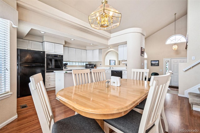 dining room featuring dark hardwood / wood-style floors, a chandelier, and a high ceiling