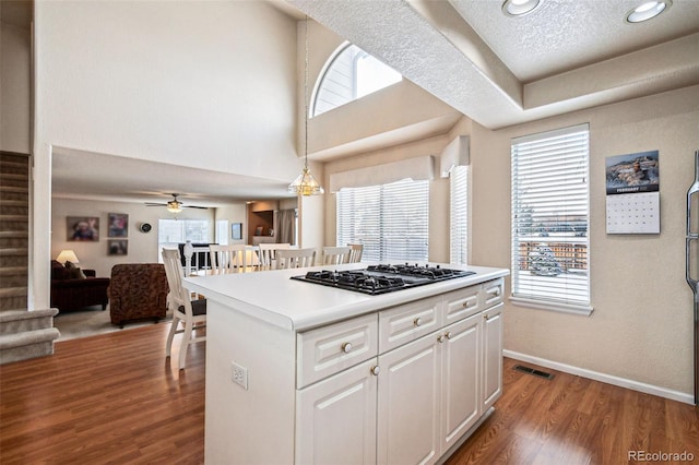 kitchen featuring white cabinetry, a center island, hanging light fixtures, hardwood / wood-style flooring, and black gas cooktop