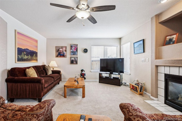 carpeted living room with ceiling fan, a tiled fireplace, and a textured ceiling