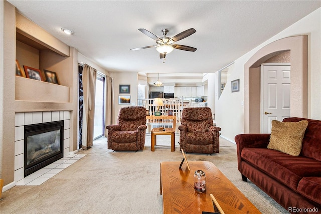 carpeted living room featuring ceiling fan and a tile fireplace