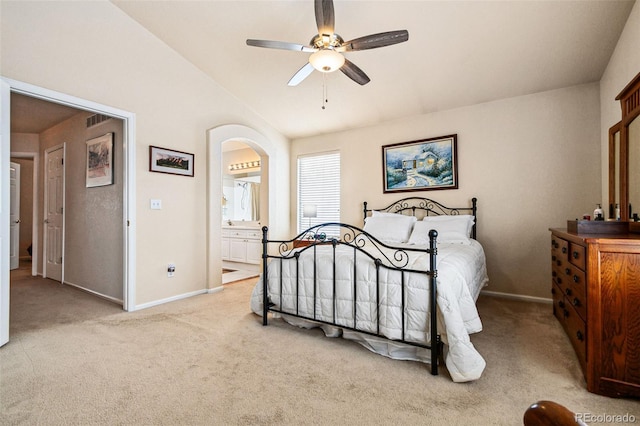 bedroom featuring lofted ceiling, ensuite bath, light colored carpet, and ceiling fan