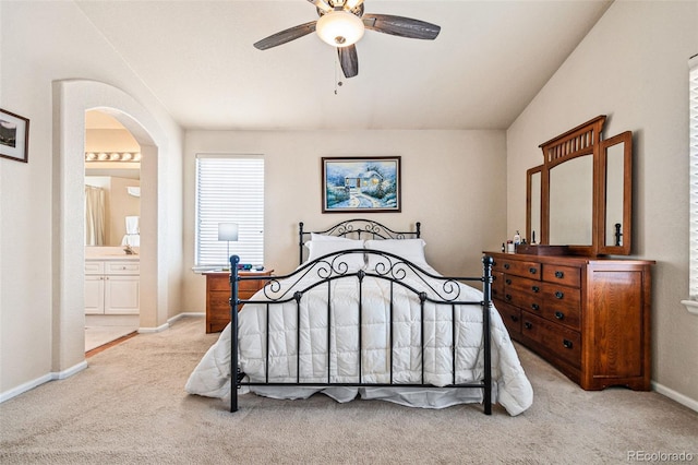 bedroom with ensuite bathroom, light carpet, and ceiling fan