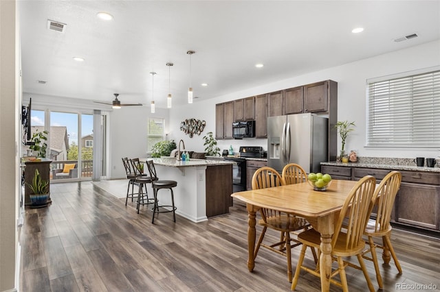 9628 Albion Ln, Thornton, CO 80229 - kitchen with black appliances, recessed lighting, dark wood-style floors, dark brown cabinets, and an island with sink