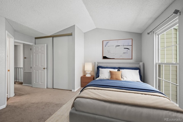 carpeted bedroom with vaulted ceiling, a closet, and a textured ceiling