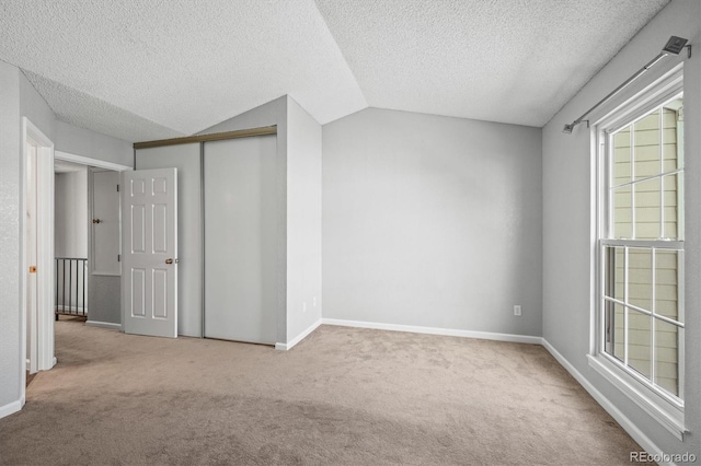 carpeted spare room featuring lofted ceiling and a textured ceiling