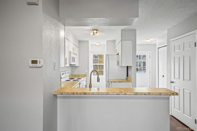 kitchen with sink, white cabinets, white appliances, kitchen peninsula, and a textured ceiling