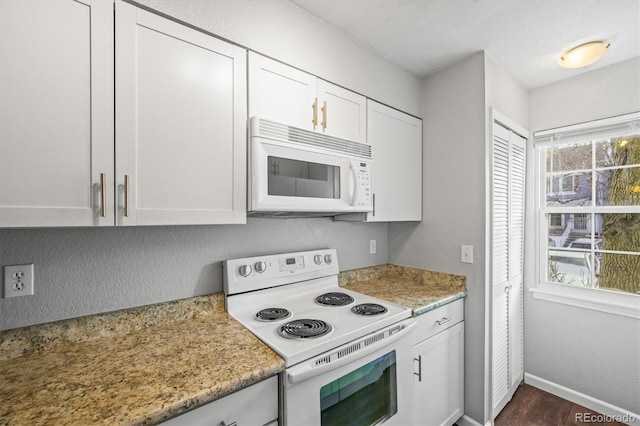 kitchen featuring white cabinetry, white appliances, and light stone counters