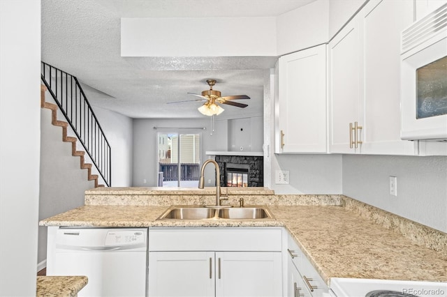 kitchen featuring dishwasher, sink, white cabinets, ceiling fan, and a textured ceiling