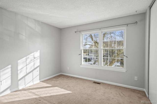 unfurnished room with light colored carpet and a textured ceiling