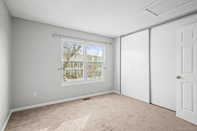 unfurnished bedroom with light carpet, a textured ceiling, and a closet