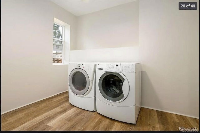 clothes washing area featuring washer and clothes dryer and light hardwood / wood-style floors