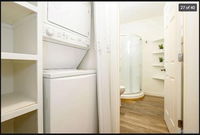 clothes washing area with light wood-type flooring and stacked washer and dryer