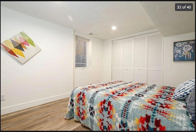 bedroom with a closet, hardwood / wood-style floors, and a textured ceiling