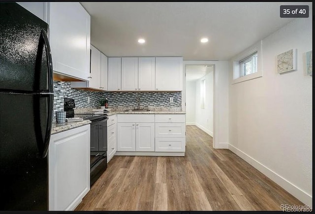 kitchen featuring sink, light hardwood / wood-style floors, white cabinetry, and black appliances